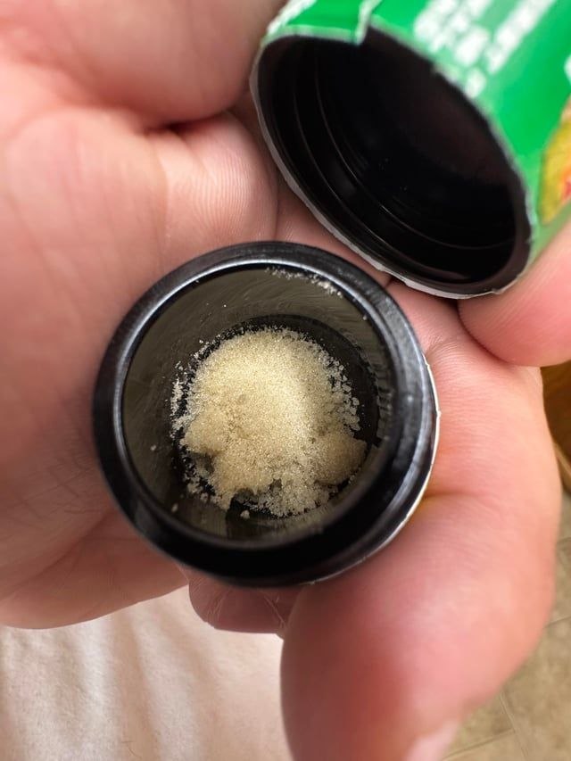 Glass jar of Lemon Up rosin with golden concentrate inside.